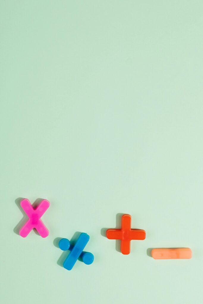 Bright plastic math symbols for arithmetic on a pastel green background with copy space.