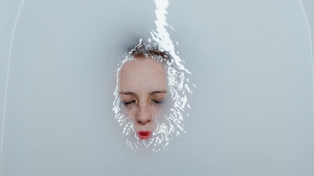 A serene moment of solitude with a woman underwater in a bathtub, evoking emotion.